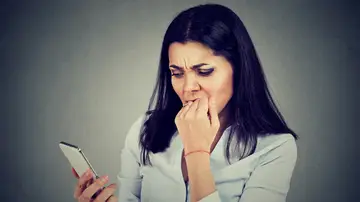 Mujer inquieta al revisar el móvil