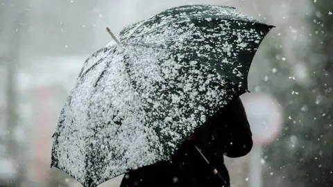 Una mujer protegiéndose de la nieve con un paraguas Una mujer protegiéndose de la nieve con un paraguas