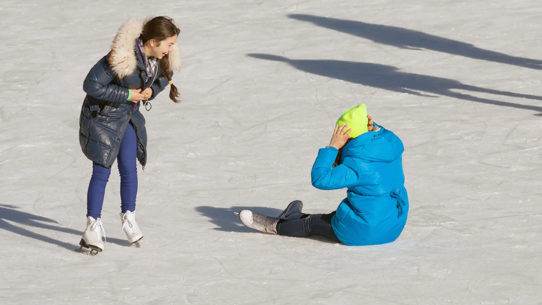 Niña riéndose de su amiga por caerse