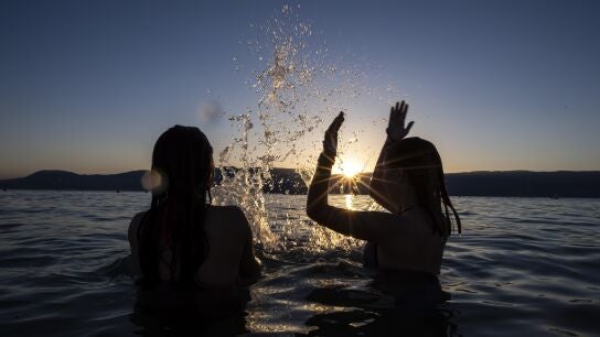Dos adolescentes disfrutan de la puesta de sol en el agua del Lago de Neuchatel