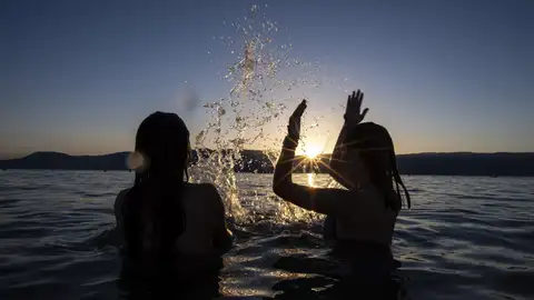 Dos adolescentes disfrutan de la puesta de sol en el agua del Lago de Neuchatel Dos adolescentes disfrutan de la puesta de sol en el agua del Lago de Neuchatel