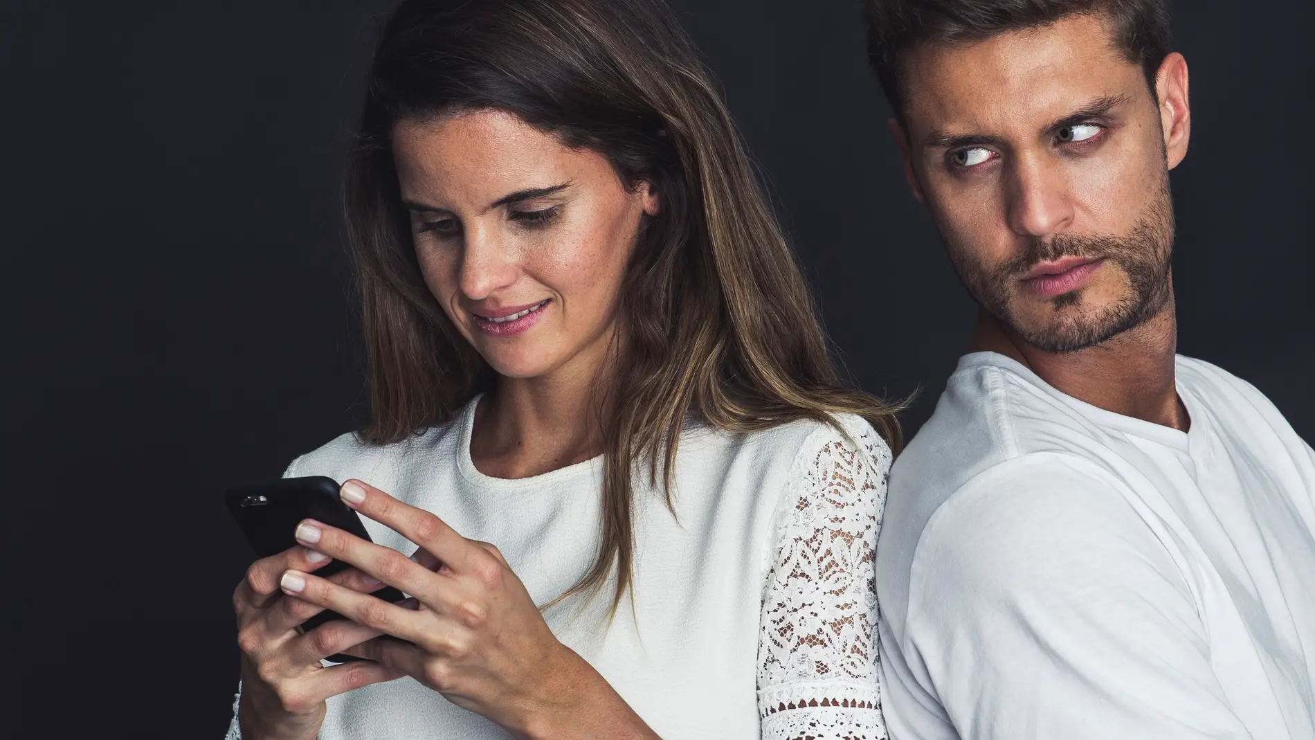 Pareja celosa, mirando de reojo el móvil.