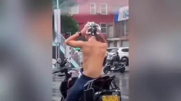 Un hombre aprovecha la lluvia para lavarse el pelo en un semáforo y acaba multado