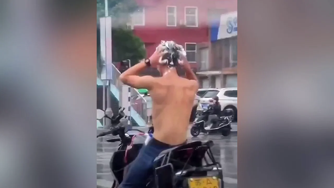 Un hombre aprovecha la lluvia para lavarse el pelo en un sem&aacute;foro y acaba multado