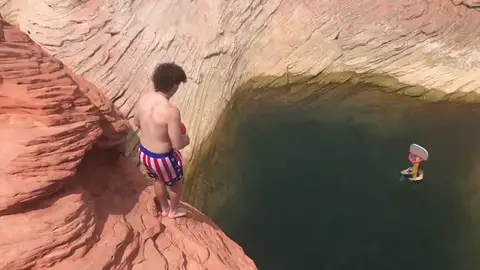 Un chico realiza un complicado truco antes de encestar la pelota en una canasta Un chico realiza un complicado truco antes de encestar la pelota en una canasta