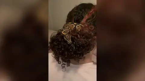 Una trabajadora de un zoo usa una serpiente como coletero Una trabajadora de un zoo usa una serpiente como coletero