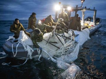 Soldados de la Fuerza Marítima a bordo de una lancha en el momento en el que recuperan una lona blanca