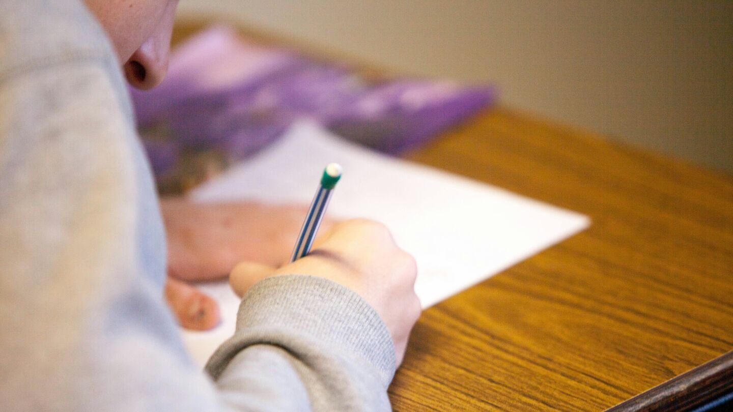 Mano de ni&ntilde;o escribiendo en un examen