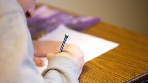 Mano de niño escribiendo en un examen Mano de niño escribiendo en un examen