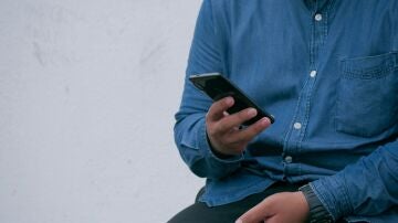 Imagen de archivo de un hombre mirando su m&oacute;vil