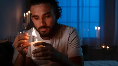 Imagen de un hombre encendiendo una vela Imagen de un hombre encendiendo una vela