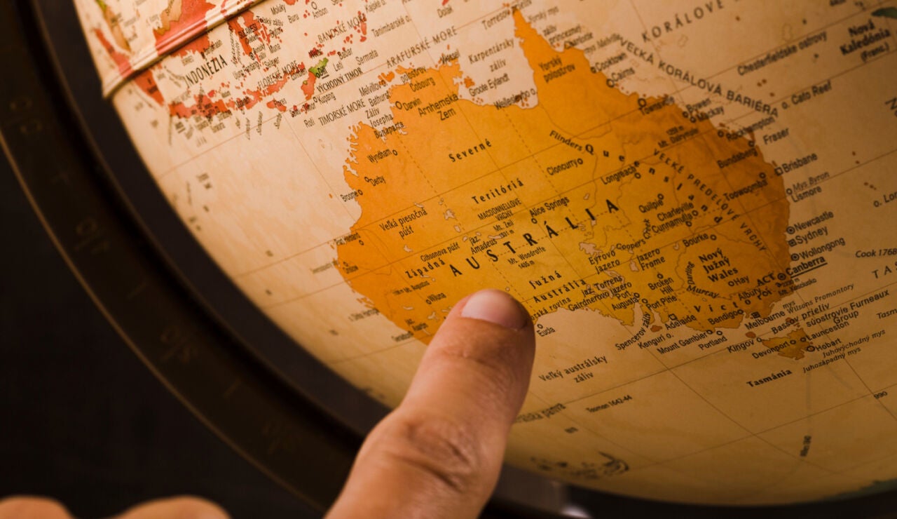 Imagen de un dedo se&ntilde;alando Australia en el mapa
