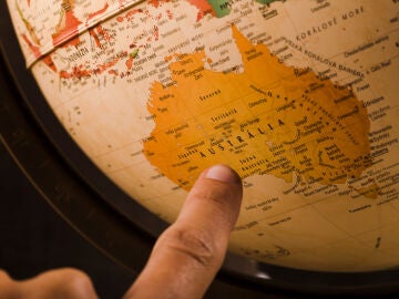 Imagen de un dedo se&ntilde;alando Australia en el mapa