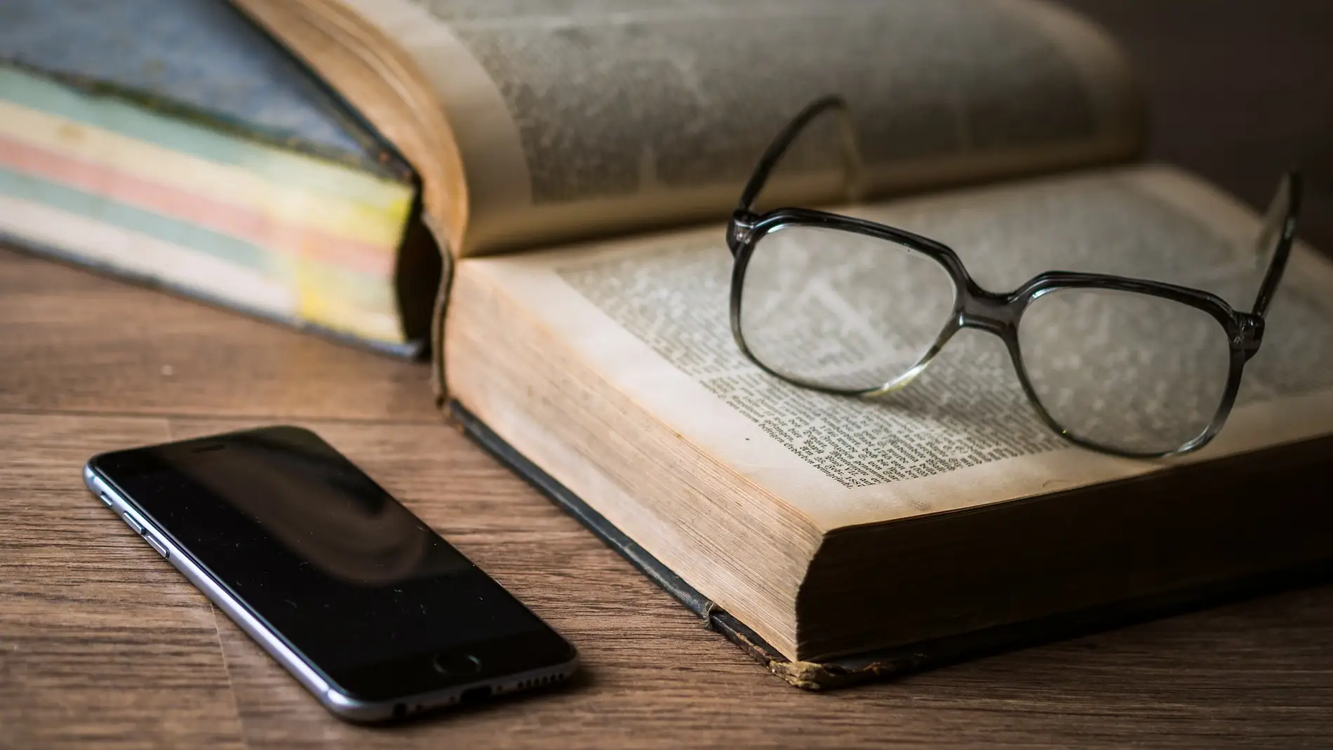 Imagen de un libro, unas gafas y un teléfono móvil