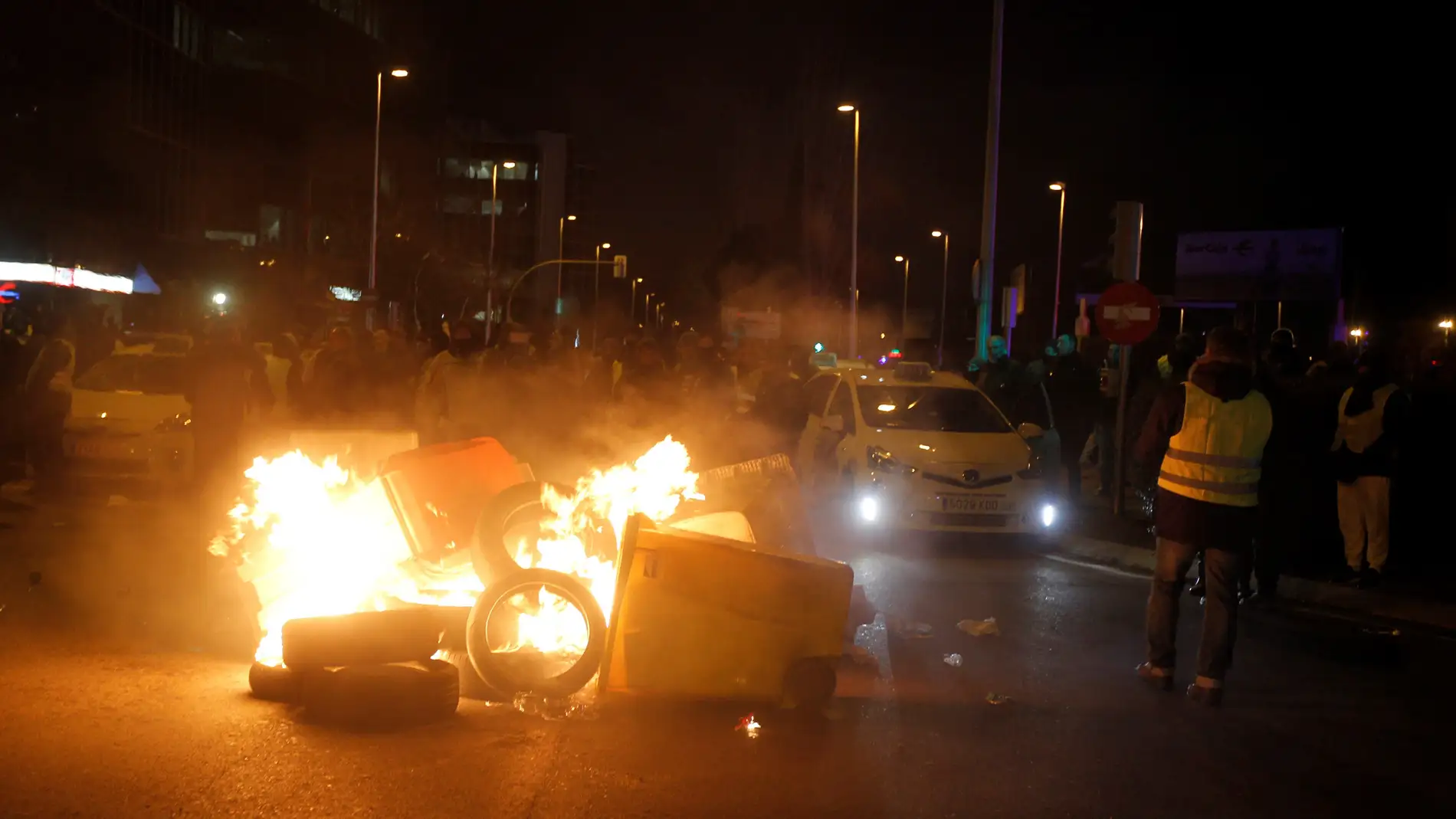 Taxistas queman contenedores en la entrada de IFEMA, en Madrid.