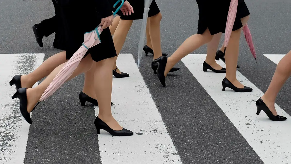 Varias mujeres cruzan un paso de cebra con tacones