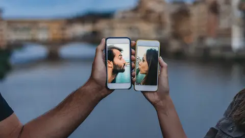 Pareja besándose a través de un móvil. Pareja besándose a través de un móvil.