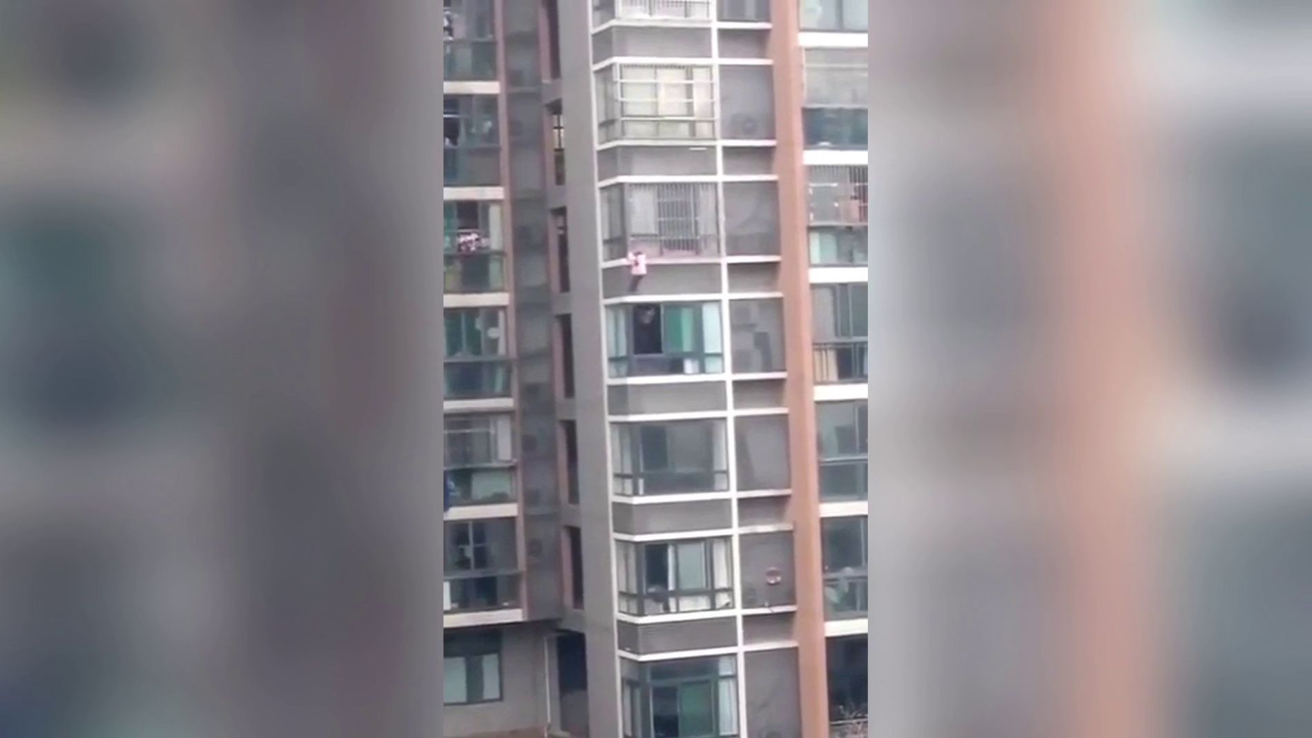 Ni&ntilde;a colgando de un edificio