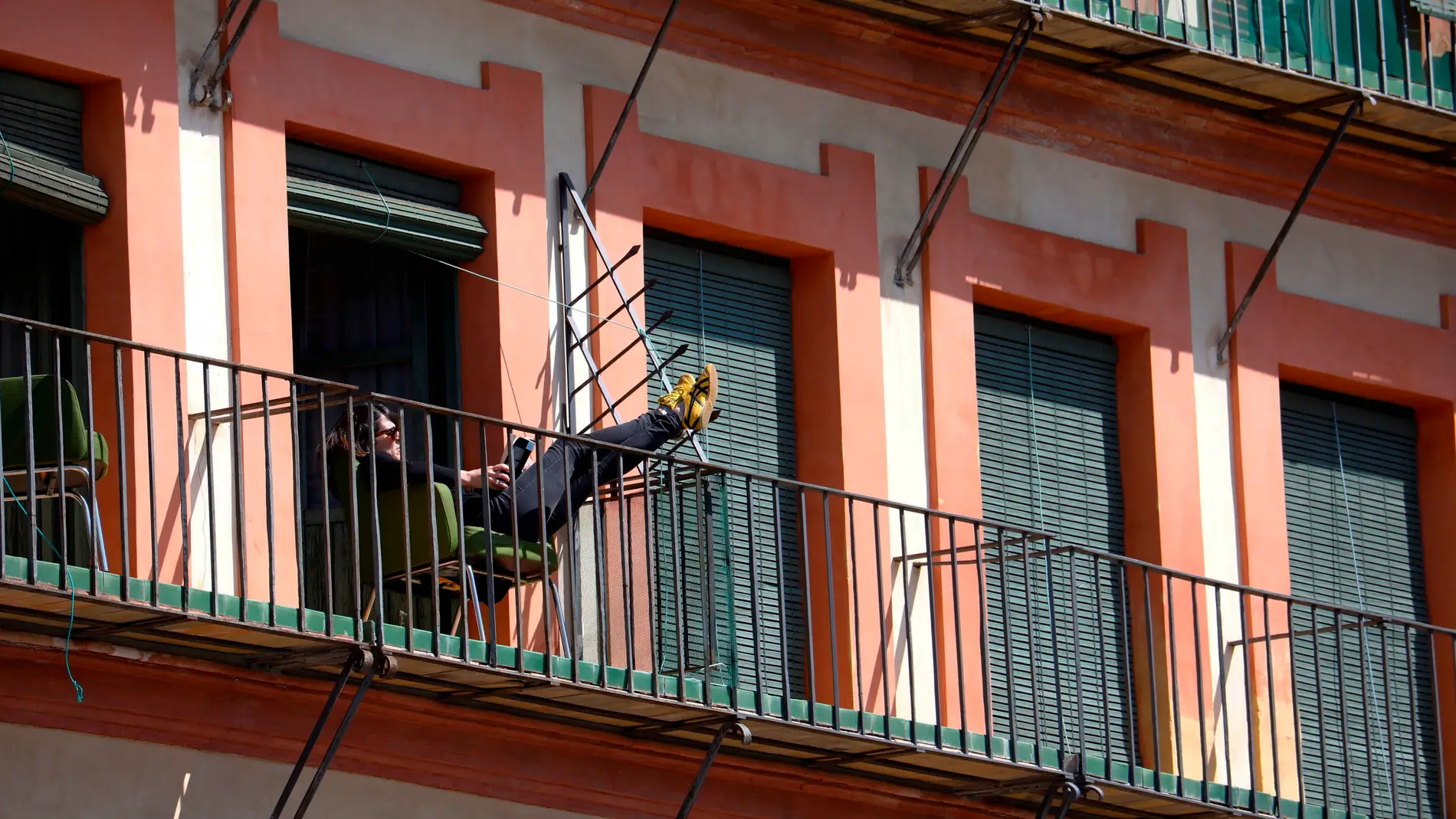 Un hombre toma el sol y lee en un balcón en Córdoba, durante la cuarentena