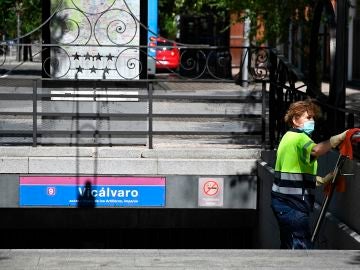 Una operaria limpia la barandilla de acceso del metro del barrio madrileño de Vicálvaro