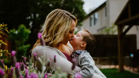 Una madre dándole un piquito a su hijo Una madre dándole un piquito a su hijo