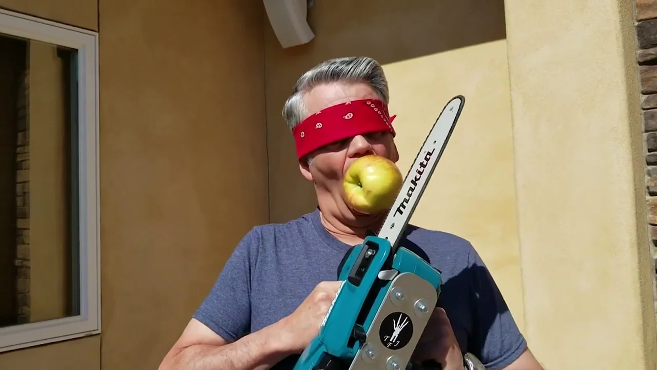 Corta una manzana con una motosierra mientras la sujeta con su boca Corta una manzana con una motosierra mientras la sujeta con su boca