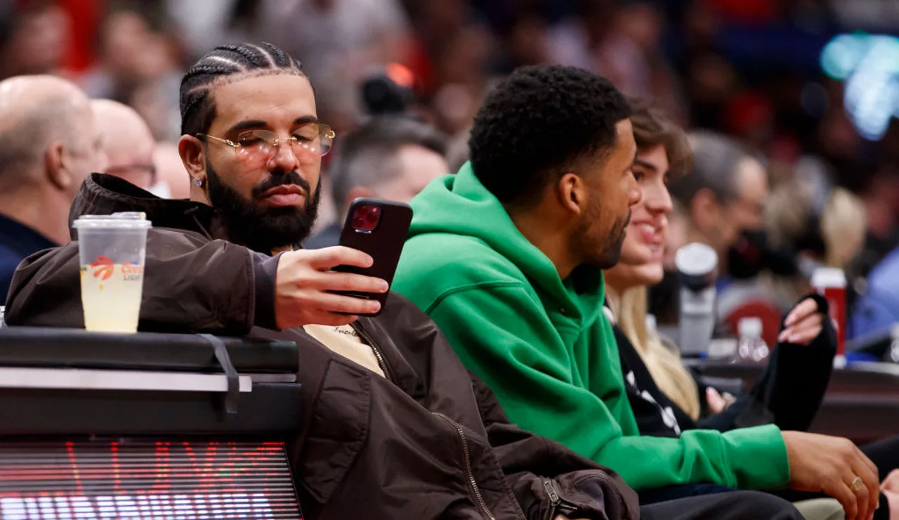 Drake mirando el móvil durante un partido de la NBA