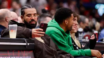 Drake mirando el móvil durante un partido de la NBA