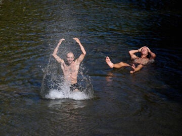 Dos hombres se refrescan en el río Arga
