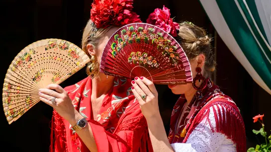Dos mujeres vestidas de flamenca evitan mirar a los borrachos en el Real de la Feria de Abril de Sevilla Dos mujeres vestidas de flamenca evitan mirar a los borrachos en el Real de la Feria de Abril de Sevilla
