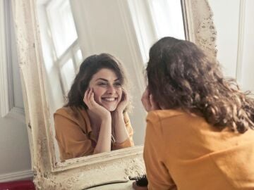 Imagen de una mujer sonriente mir&aacute;ndose al espejo