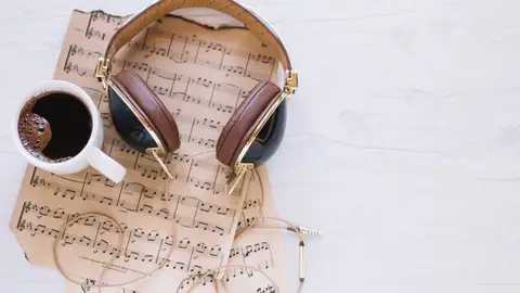Imagen de unos auriculares y un café sobre una partitura Imagen de unos auriculares y un café sobre una partitura