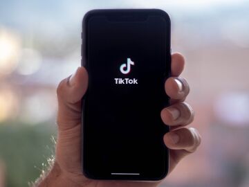 Imagen de una mano sosteniendo un tel&eacute;fono con TikTok abierto