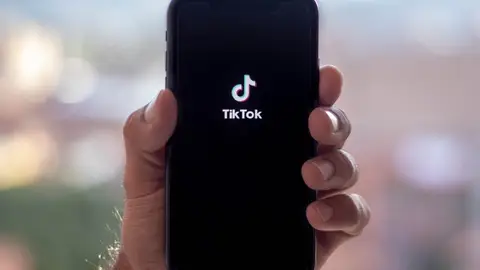 Imagen de una mano sosteniendo un teléfono con TikTok abierto Imagen de una mano sosteniendo un teléfono con TikTok abierto