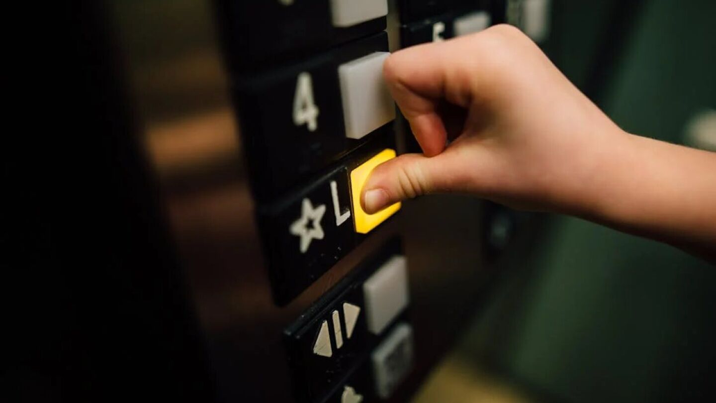Imagen de una mano pulsando el bot&oacute;n de un ascensor