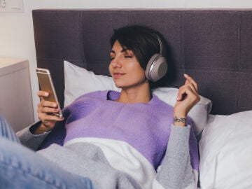 Mujer escuchando un podcast en la cama