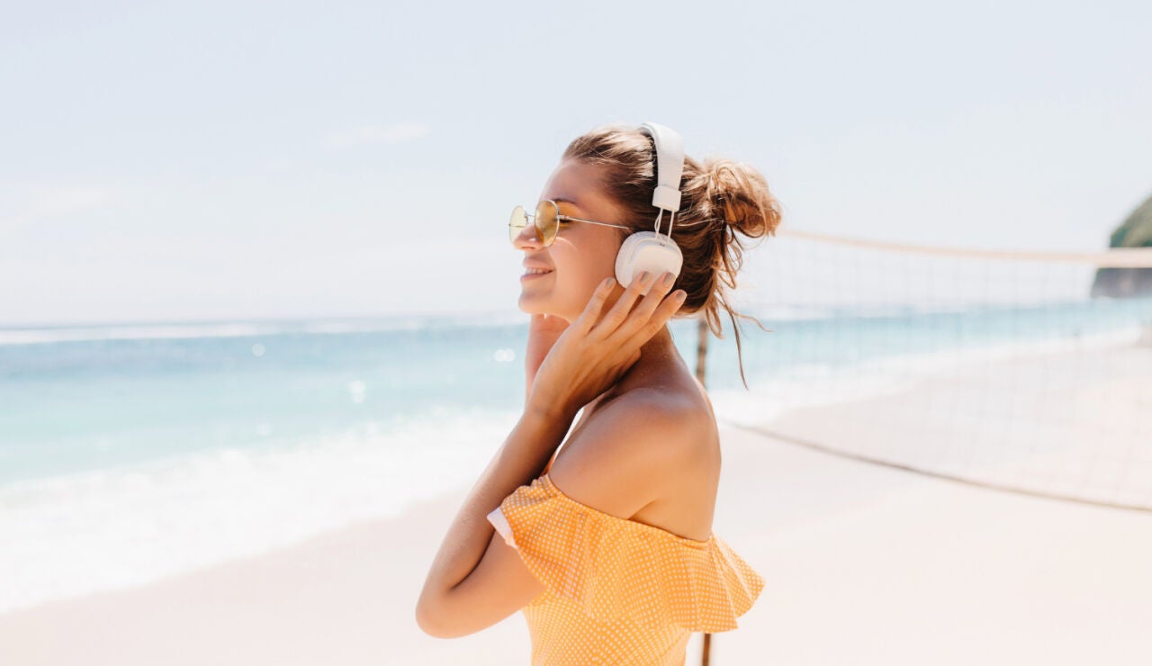 Imagen de una mujer escuchando m&uacute;sica en la playa