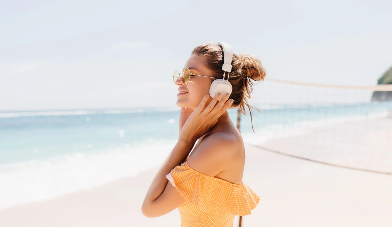 Imagen de una mujer escuchando música en la playa