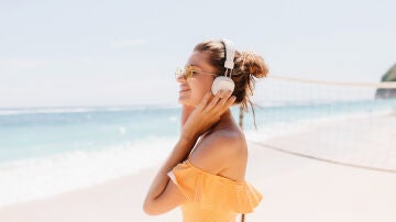 Imagen de una mujer escuchando m&uacute;sica en la playa