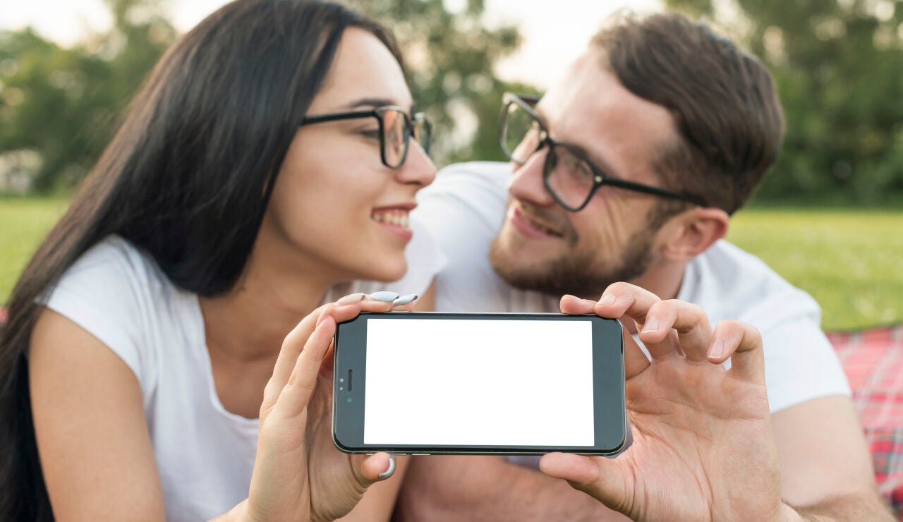 Imagen de dos personas enamoradas y un m&oacute;vil